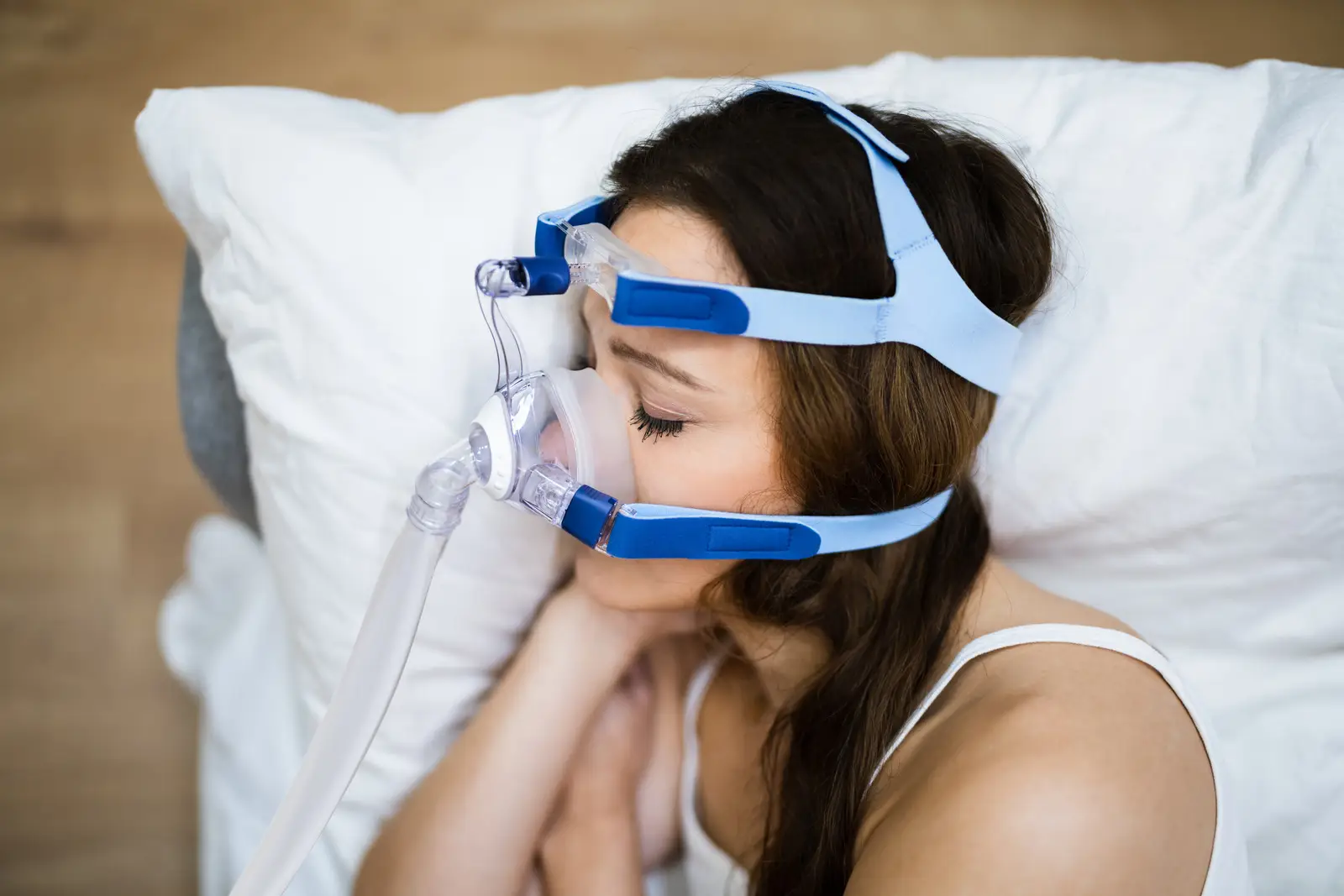 Femme dormant avec un masque CPAP pour traiter l’apnée du sommeil, allongée sur un oreiller blanc.