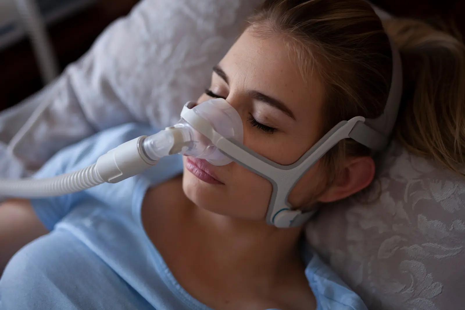 Femme dormant paisiblement avec un masque CPAP, utilisé pour le traitement de l'apnée du sommeil.